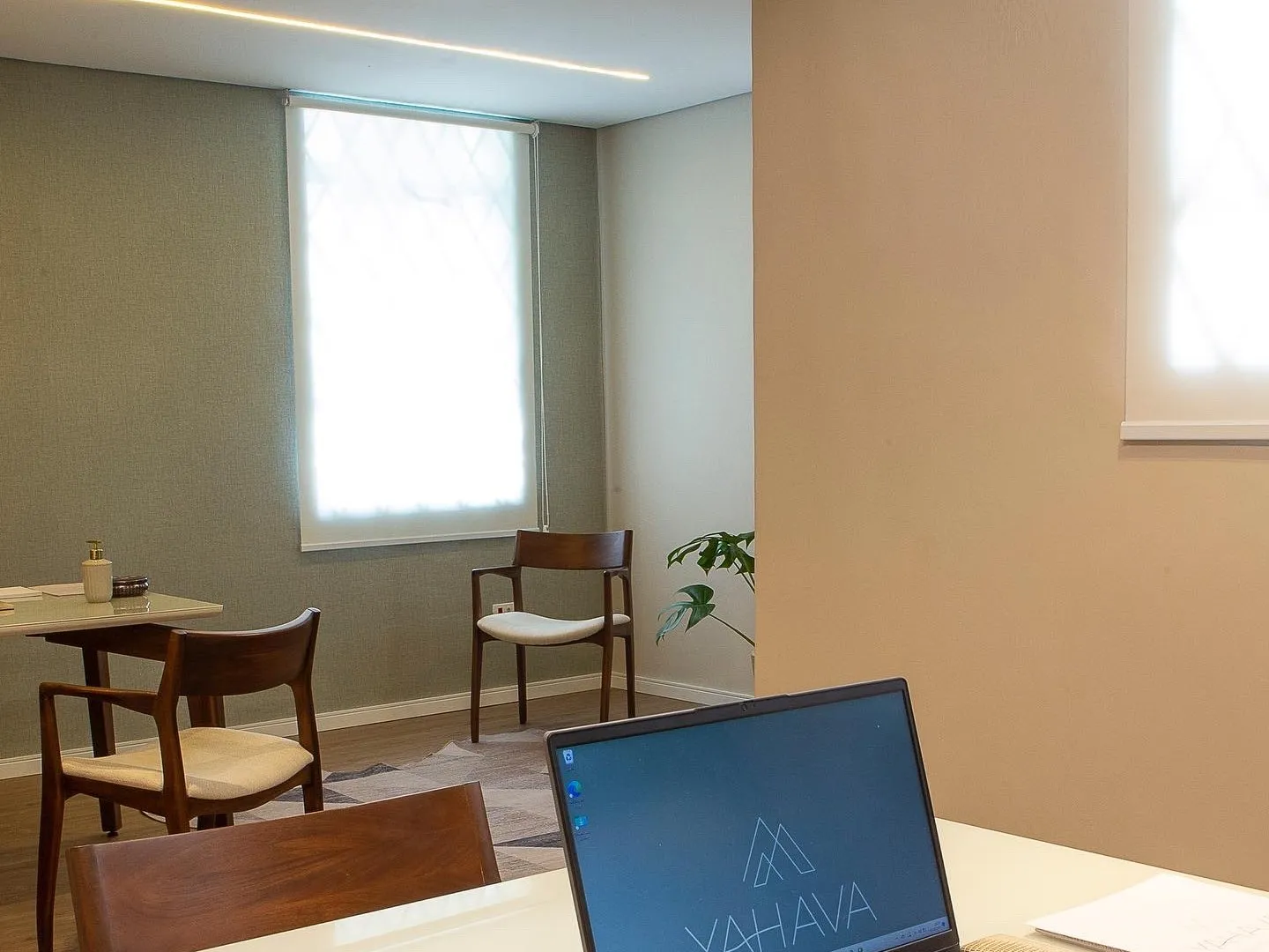 Sala da recepção da Casa Yahava, com cadeiras de madeira, janela e o balcão com o computador da casa